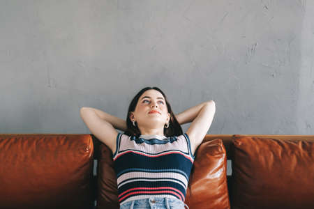 Young calm caucasian woman relaxing lying on comfortable sofa in modern living room, lazy happy...