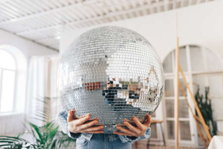 Young woman holding big disco ball in hands. High quality photo