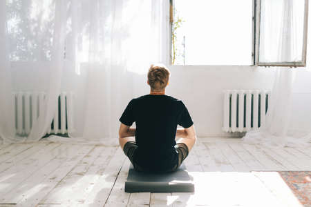 Young caucasian man meditate, doing yoga indoors at home. Staying fit and healthyの写真素材