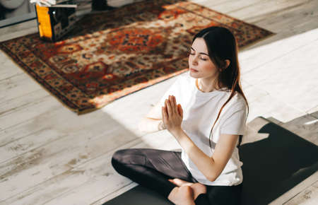 Beautiful brunette fitness woman meditate, doing yoga indoors at home. Staying fit and healthyの写真素材