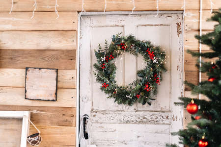 Wooden white door to the house decorated with Christmas wreath. High quality photoの写真素材