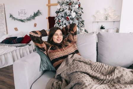 Young caucasian woman relaxing on a sofa at home in christmas holidays. High quality photoの写真素材