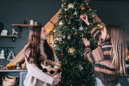 Two young women friends decorates the Christmas tree with toys. Preparing for the holidays. High quality photoの写真素材