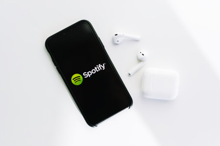 Spotify logo on the iPhone screen, with AirPods. High quality photo