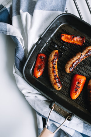 Sausages and bell peppers in a grill pan with vegetables. High quality photo