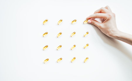 Omega-3. Fish fat oil capsules in spoon on a white background.の写真素材