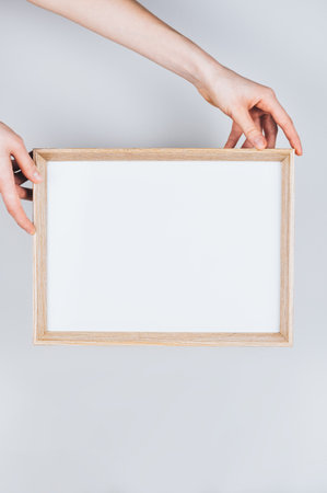 Woman hands holding a wooden frame with a clear blank white background. High quality photo