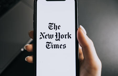 Hands holding iPhone X with The New York Times logo on the screen. Copy space.のeditorial素材