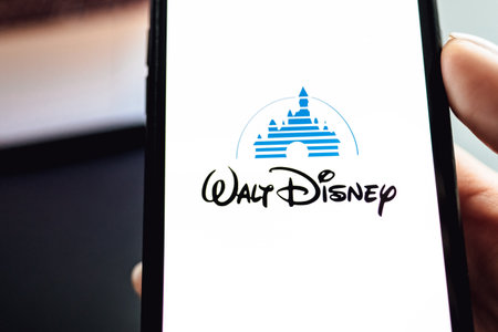 Hand holding the iPhone X with Disney logo on the screen. Copy space.