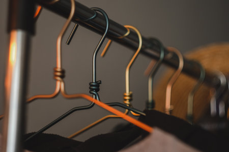 Metal clothes hanger, warm light, close-up. Fashion concept, wardrobe. High quality photo