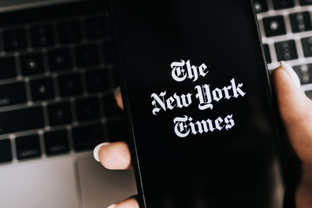 Hands holding iPhone X with The New York Times logo on the screen. Copy space.のeditorial素材