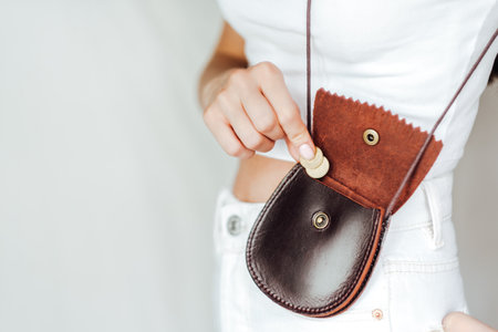 Girl puts a coin in the leather purse, on a white background.の写真素材