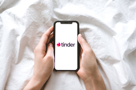 Tinder app logo on the smartphone screen in woman hands. Copy space. Top view.のeditorial素材