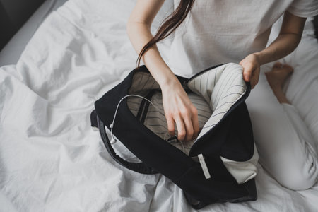 Woman packs gear, accessories in a backpack, sitting at home on the bed. High quality photoの写真素材