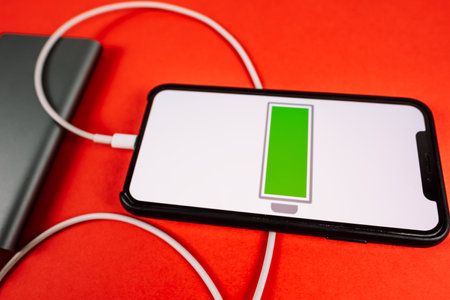 Smartphone on a red background with a low battery icon on the screen. High quality photo.の写真素材