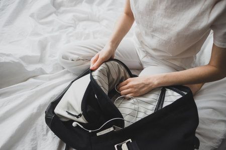 Woman packs gear, accessories in a backpack, sitting at home on the bed. High quality photo