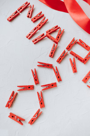 March 8 text from red holiday clothespins. Close up.