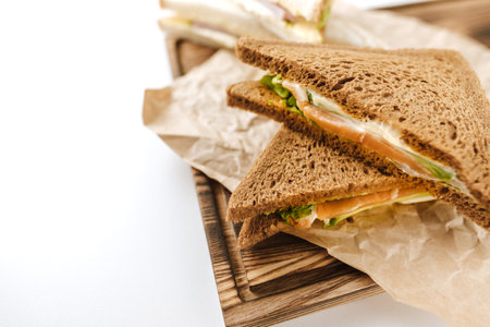Dark and white bread sandwiches on a wooden board, isolated on white background.の写真素材