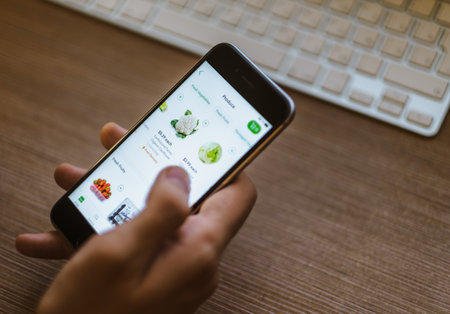 A man uses an application on a smartphone to deliver food and vegetables. High quality photoのeditorial素材