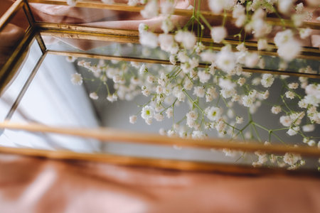 Spring composition, white gypsophila flowers with gold mirror on the gold satin fabric.