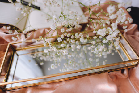 Spring composition, white gypsophila flowers with gold mirror on the gold satin fabric.