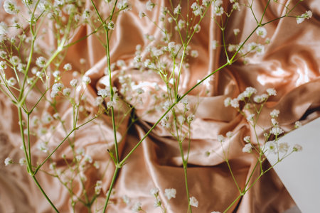 Spring background, white gypsophila flowers on the gold satin fabric.