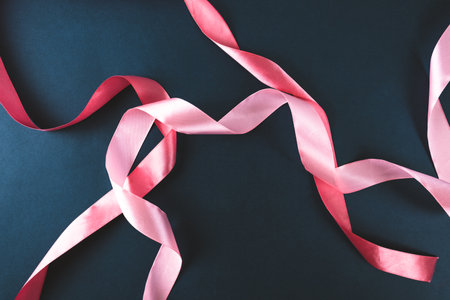 Pink ribbon on a dark blue background. abstraction. High quality photo.