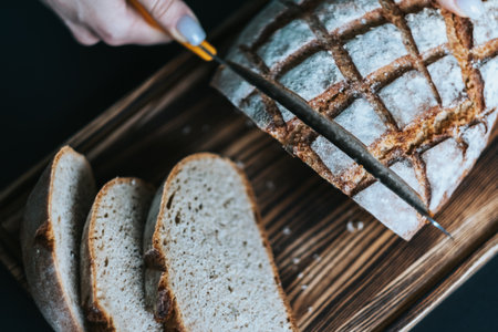 Woman slices fresh homemade bread on a wooden board. Top view.の写真素材