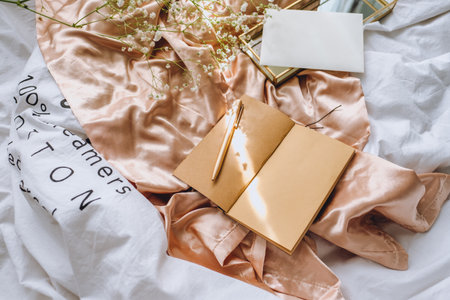 Spring composition, white gypsophila flowers with notebook and magnifying glass on the gold satin fabric.の写真素材