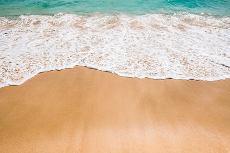 Soft blue waves with foam of ocean on the sandy beach background. High quality photo.