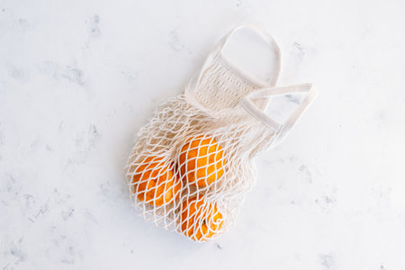 Fresh oranges in eco net shopping bag on white background. High quality photoの写真素材