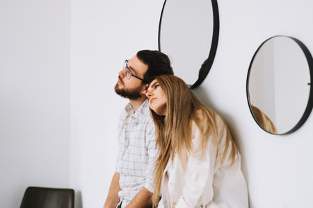 Portrait of happy couple sitting on the sofa at home near white wall. High quality photoの写真素材