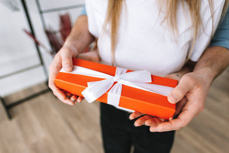 Man surprised her girlfriend with gift, happy couple celebrating valentines day or anniversary