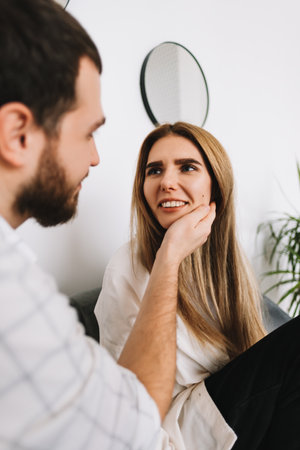 Young happy couple resting on a sofa at home, gently touching each other. High quality photoの写真素材