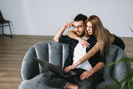 Young couple using laptop computer and resting on the sofa at home together. High quality photoの写真素材