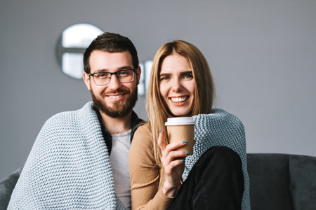 Portrait of cheerful couple sitting on the sofa at home and looking on camera. High quality photo