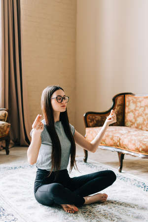 Beautiful brunette fitness woman meditate, doing yoga indoors at home. Staying fit and healthy