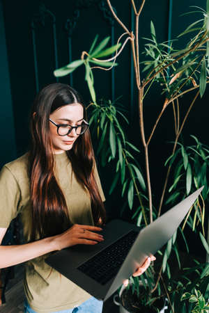 Young caucasian woman in eyeglasses working on laptop computer in home garden.の写真素材