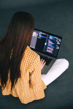 Young woman mobile developer writes program code on a computer, programmer work.の写真素材