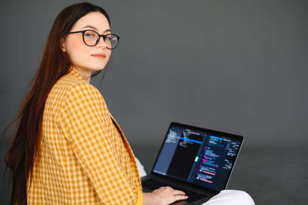 Portrait of young woman mobile developer with laptop, writes program code on a computer, programmer...