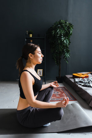 Young caucasian fitness woman meditate, doing yoga indoors at home near the bed. Staying fit and...