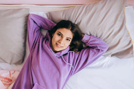 Young calm caucasian woman relaxing lying on comfortable bed in the morning, lazy happy woman resting at home.の写真素材
