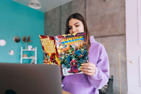 Young woman reading comic books at home.のeditorial素材