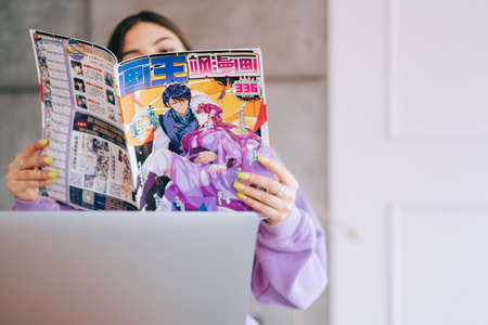 Young woman reading manga comic book at home.のeditorial素材