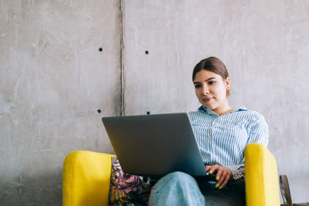 Young woman mobile developer with laptop, writes program code on a computer, programmer work in modern office.の写真素材