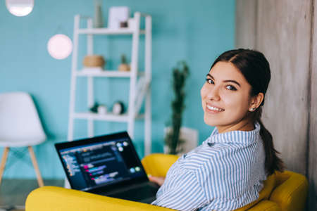 Portrait of young woman mobile developer with laptop, writes program code on a computer, programmer work.の写真素材