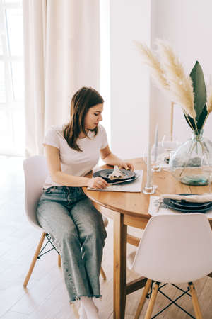 Young caucasian woman sitting on a chair at the kitchen table at home.の写真素材