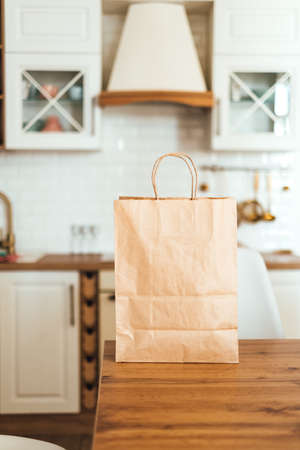 Eco shopping paper bag on the table in modern kitchen. Food delivery or market shopping concept.の写真素材