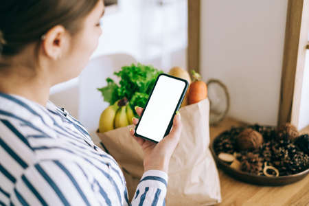 Woman hold the smartphone with white screen, mock up. Online food market concept.の写真素材