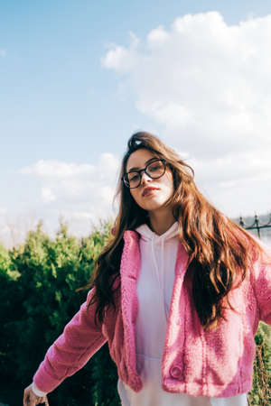 Portrait of young caucasian woman with brunette hair in eyeglasses and stylish clothing, outdoor.の写真素材